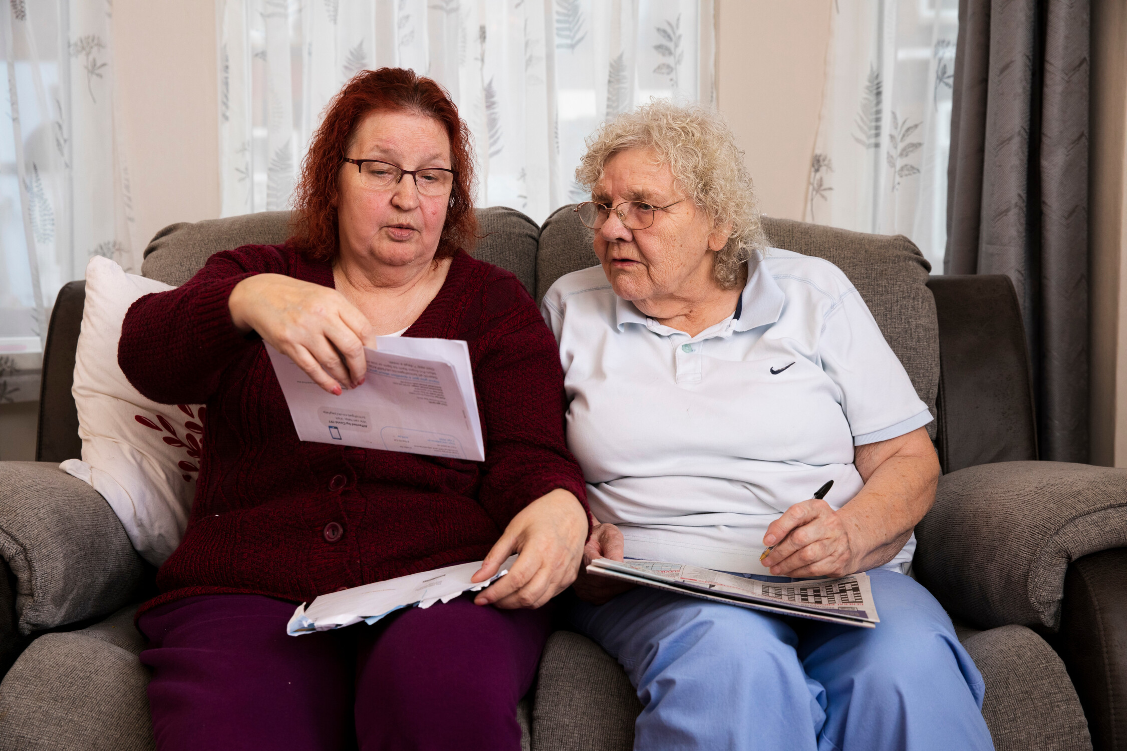 Two women sat at home together looking at a book.