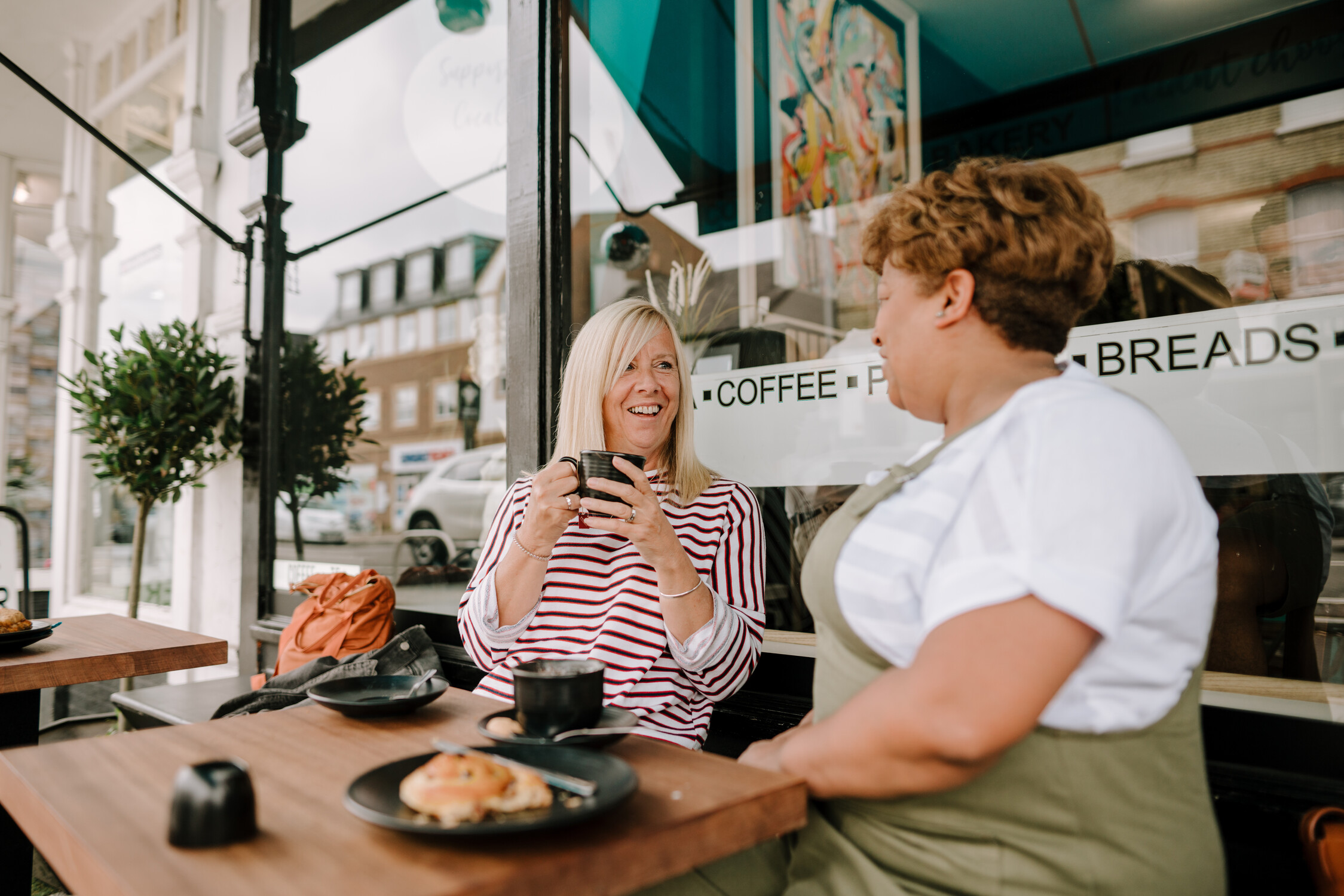 Two women are sat together drinking coffee in a coffee shop