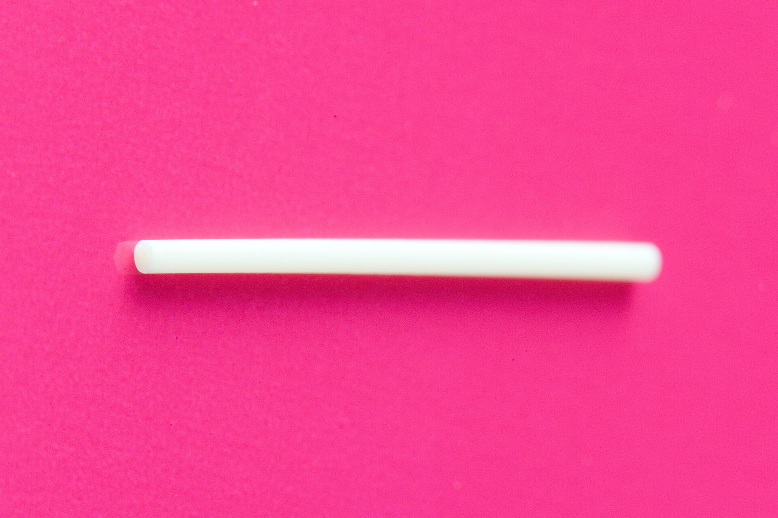 A contraceptive implant on a bright pink background