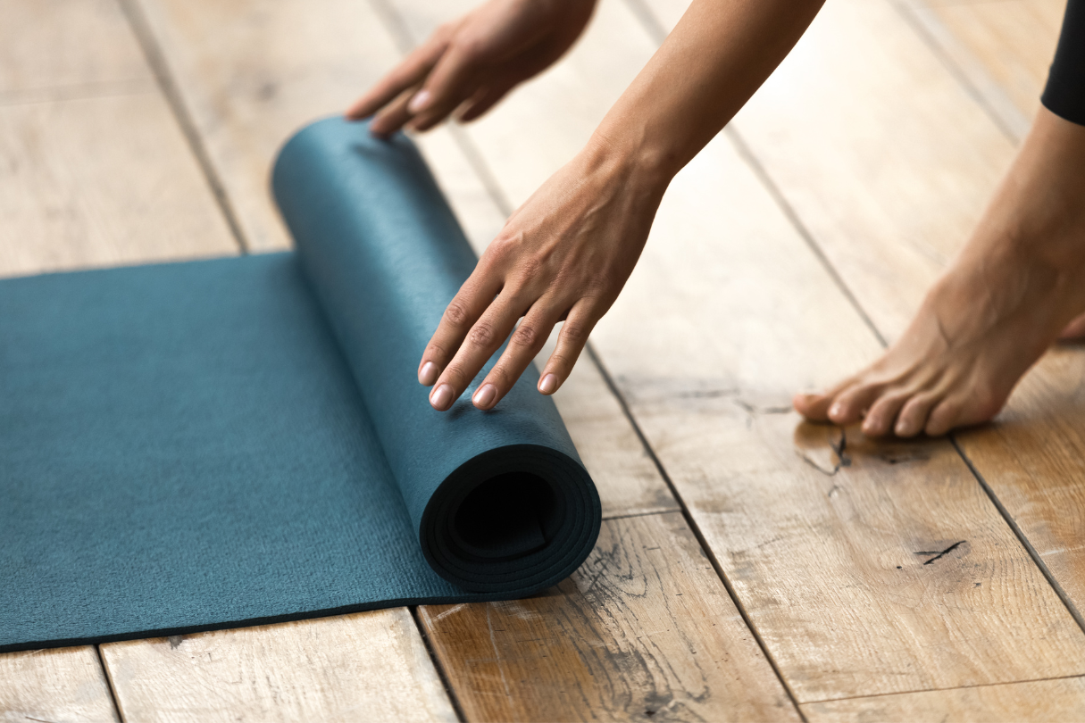 eye test (10) A lady stands at the foot of a yoga mat, rolling it up.